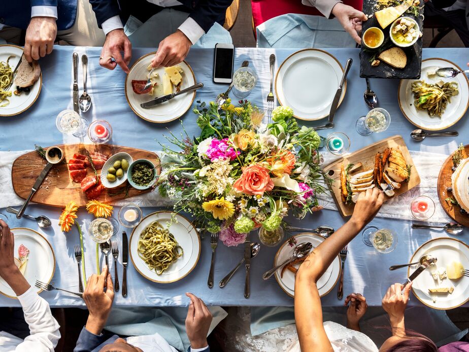 A top-down view of a beautifully set dining table with gourmet dishes, colourful floral arrangements, and elegant tableware.